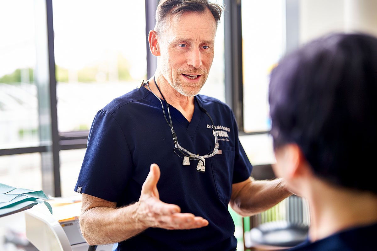 Zahnarzt Dr. Gerald Schillig von der Zahnarztpraxis Podbi344 in Hannover berät einen Patienten zur Zahnbehandlung