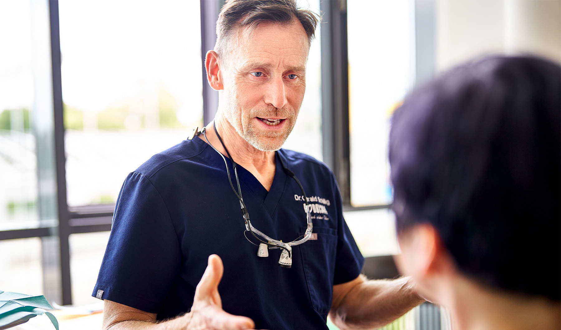 Zahnarzt Dr. Schillig von der Zahnarztpraxis Podbi344 in Hannover berät einen Patienten zu Zahnbehandlungen.