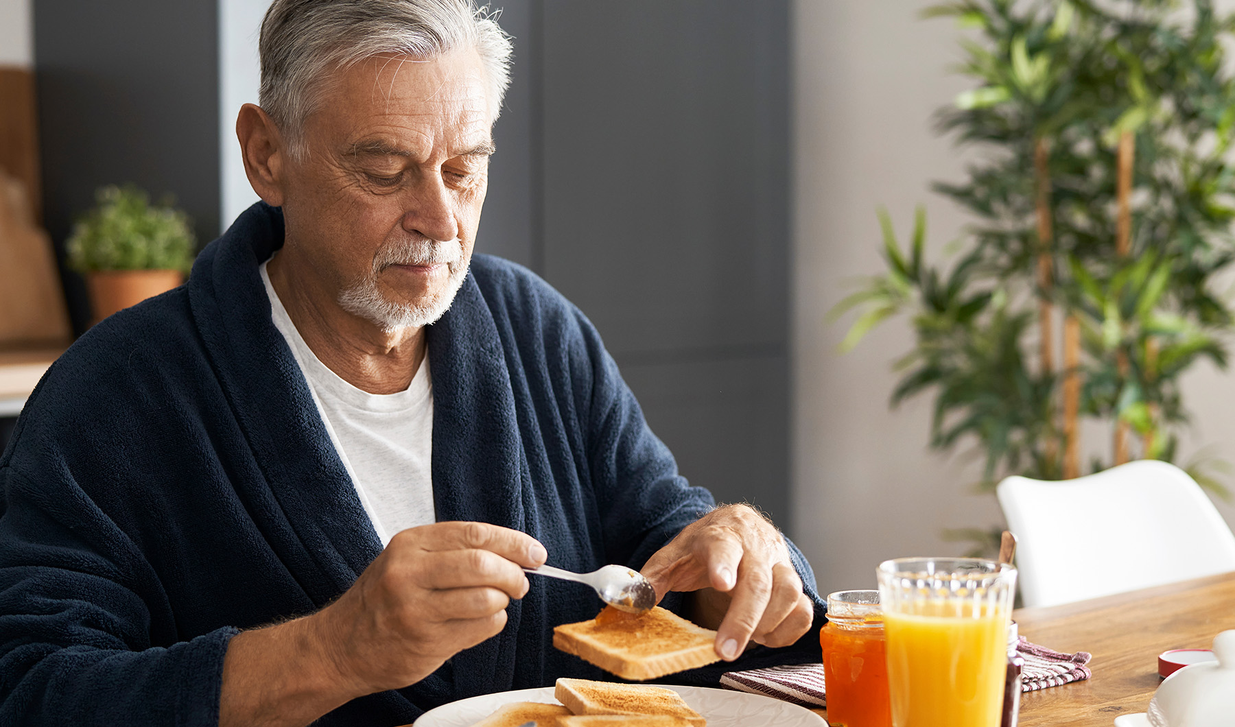 Ein älterer Mann frühstückt; gesunde Ernährung ist wichtig für Ihre Mundgesundheit. Besuchen Sie Zahnarzt Dr. Schillig in Hannover.