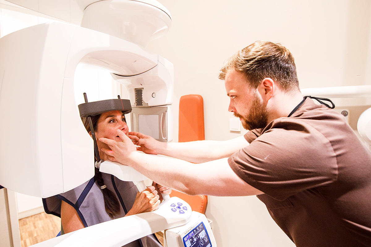 Zahnarzt bei Dr. Schillig in Hannover bereitet eine Patientin für eine digitale Röntgenaufnahme in der modernen Zahnarztpraxis Podbi344 vor.