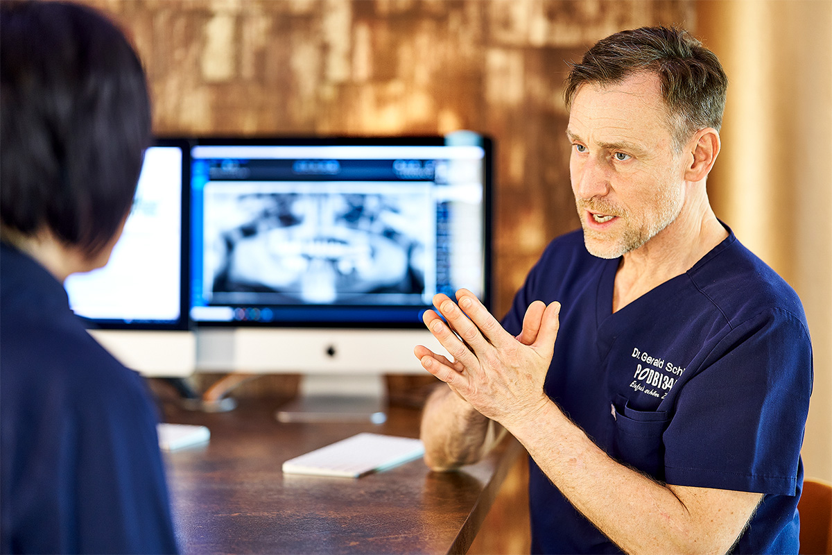 Zahnarzt Dr. Gerald Schillig von Podbi344 in Hannover erklärt einen Röntgenbefund. Ihre kompetente Zahnarztpraxis für Zahnbehandlung und Mundgesundheit.